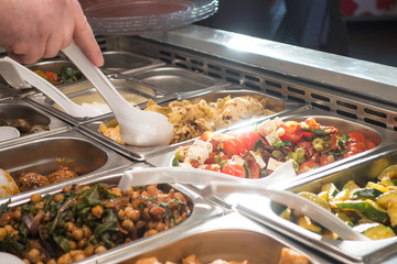 Mann bei Selbstbedienung an Salatbüffet in Kantine zum Mittagessen