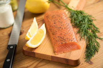 Geräucherter und gebeizter Lachs auf Holzbrett mit Lachsmesser und Soßen