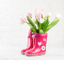 red boots with tulips on wooden background
