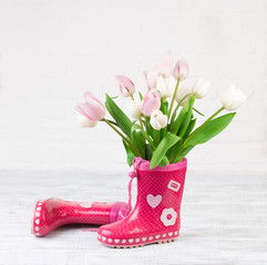 red boots with tulips on wooden background