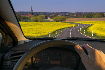 driver behind the wheel driving down a country road