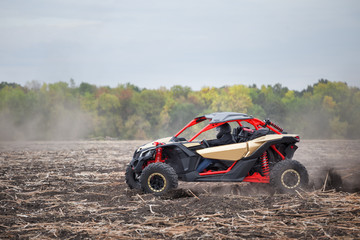 Obraz na płótnie Canvas Red quad bike with a driver in plowed field