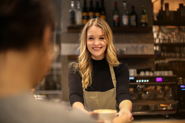 Smiling waitress serving a hot drink - obrazy, fototapety, plakaty