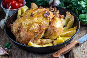 Whole roasted chicken with potato on a pan