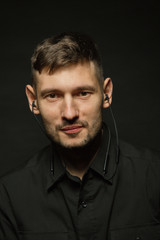 Man in headphones and black shirt on a black background