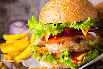 Close up of cheeseburger and french fries on a wooden table