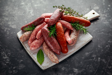 Freshly made raw breed butchers sausages mix in skins with herbs on white cutting board.