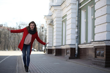 Pretty girl on a walk in red coat in the city