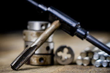 Metalwork tools on the workshop table. Threading dies and taps in an old dusty workshop.