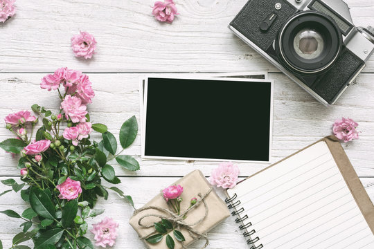 vintage retro camera and pink rose flowers bouquet with blank photo frame, lined notebook and gift box