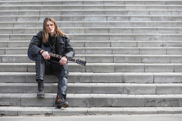 Rock guitarist on the steps. A musician with a bass guitar in a 