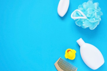Baby bath products/ Yellow rubber duck, soap, shampoo, wooden comb and sponge on a blue background