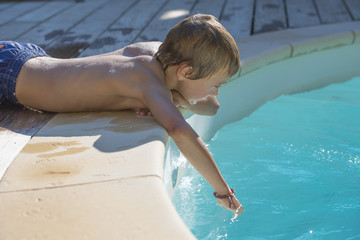 enfant touchant l'eau de la piscine