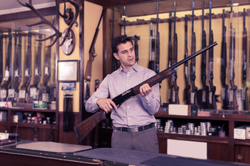 Fototapeta na wymiar Male standing with shotgun indoors in hunting shop