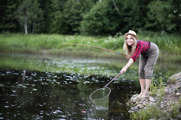 Girl by the river with a fishing rod