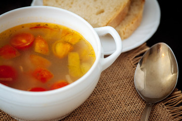 Fish soup with cherry tomatoes on a black textural background.