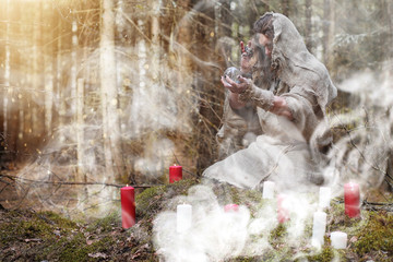 A man in a cassock spends a ritual in a dark forest