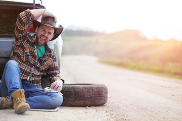 Man is sitting on the road by the car