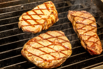 The chef cooks steaks on the grill.
