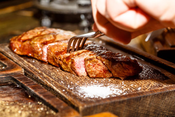 Beef steak ribeye and Striploin are on the Board and cut.