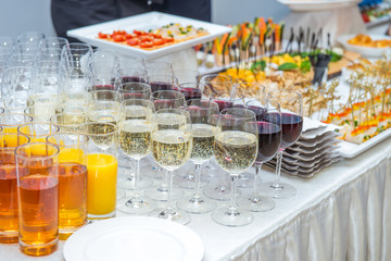 Catering table with alcoholic and non-alcoholic drinks, dishes and snacks food on the event. Service at business meeting, party, weddings. Selective focus, space for text.