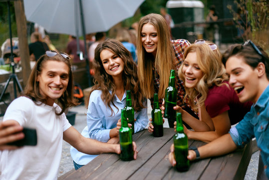 Group Of Friends Drinking Beer And Taking Photos On Phone