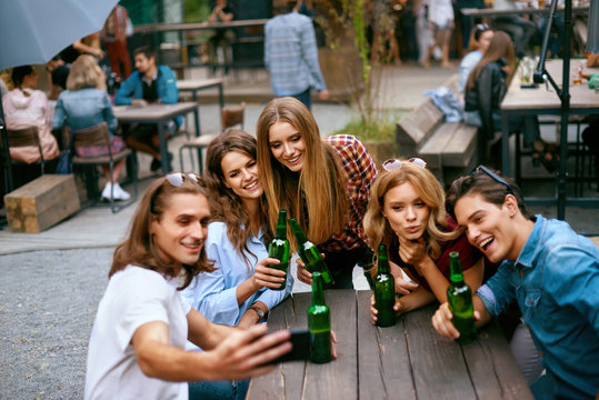 Group Of Friends Drinking Beer And Taking Photos On Phone