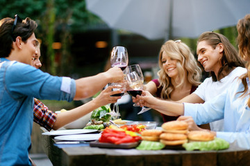 Friends Toasting With Drinks At Dinner Party Outdoors
