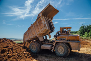 Fototapeta premium Dump truck unloads soil with crashed stone