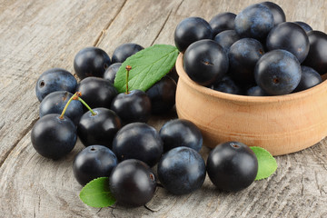blackthorn berries with green leaf on old wooden table