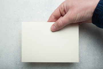 Obraz premium A5 flyer in a male hand on a white vintage background.