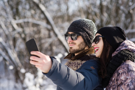 Smiling couple making selfie in winter outdoors
