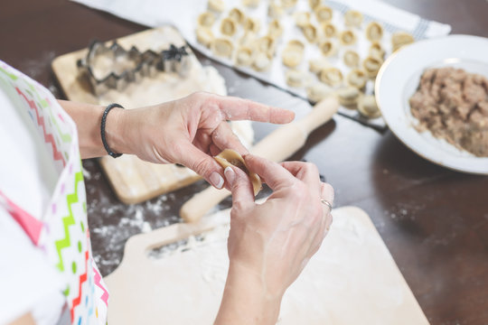 The process of making delicious homemade dumplings. On the kitchen table is laying a filling, ready-to-eat dumplings and dough.