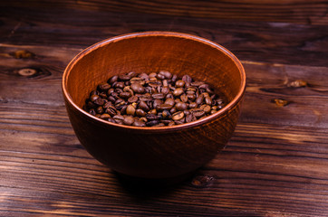 Roasted coffee beans in bowl on wooden table