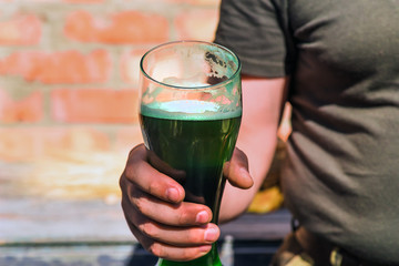 man holding a glass of green beer