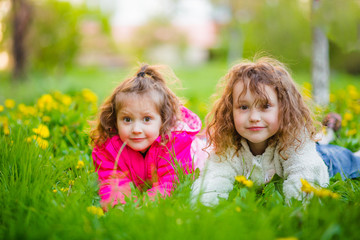 Two sisters are lying on the fresh green grass in the spring.