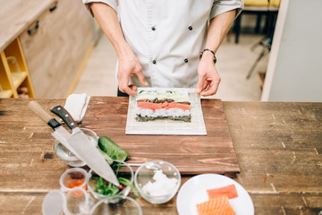 Male cook making sushi, asian kitchen