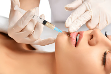 Plastic lips surgery beauty concept young brunette woman face and  doctor hand in glove with syringe