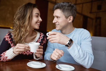 Man and woman drinking coffee in a cafe. Two people, man and woman in cafe communicate, laughing and enjoying the time spending with each other. Couple in love on a date. Love story and Valentines Day