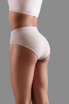 Close up of woman demonstrating fit legs and breech wearing tight underpants. Isolated on background