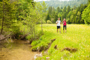 active Beautiful young couple hiking ina nature climbing hill or mountain - man and woman trekking