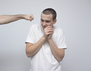 Weak young scary man trying to defend from arm punches. Protecting himself from violent attack. Agressive abuse and violence concept.Selective focus and shallow DOF.