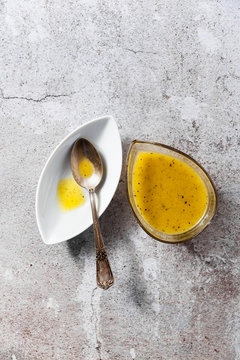 dressing for salad from olive oil and lemon in a serving dish and a silver spoon on a stone table
