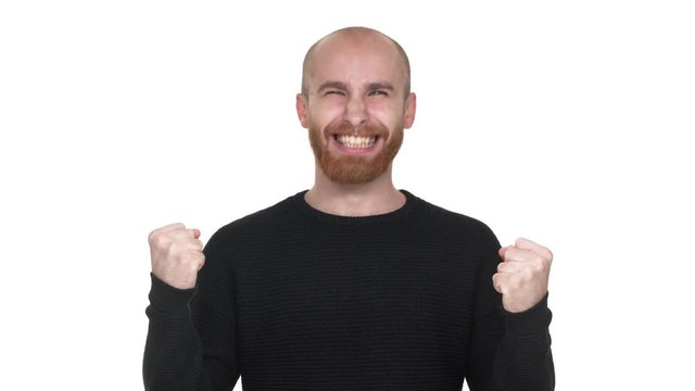Portrait of happy man rejoicing and enjoying his aims, clenching fists like winner or successful person over white background. Concept of emotions