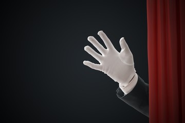 Actor behind red curtains is waving with hand.