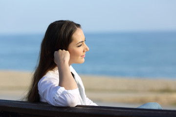 Pensive woman looking away on the beach