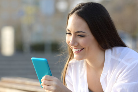 Smiley teen using a blue smart phone on the street