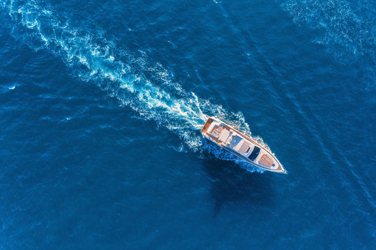 Fototapeta Yacht at the sea in Europe. Aerial view of luxury floating ship at sunset. Colorful landscape with boat in marina bay, blue sea. Top view from drone of yacht. Luxury cruise. Seascape with motorboat