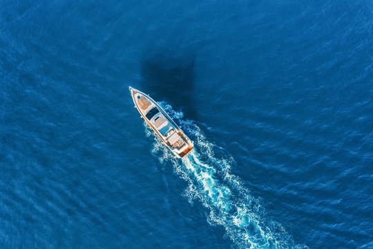 Fototapeta Yacht at the sea in Europe. Aerial view of luxury floating ship at sunset. Colorful landscape with boat in marina bay, blue sea. Top view from drone of yacht. Luxury cruise. Seascape with motorboat