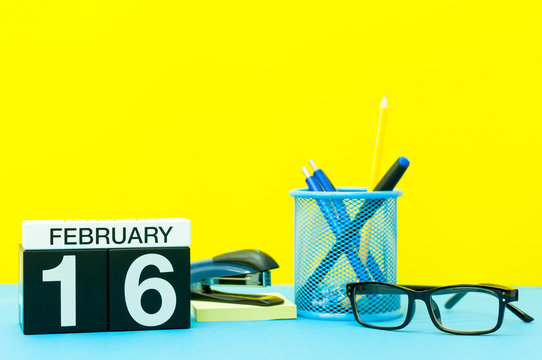 February 16th. Day 16 of february month, calendar on yellow background with office supplies. Winter time